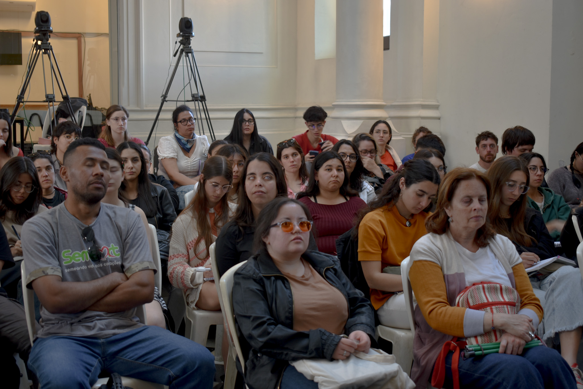 Varias personas miran atentamente hacia adelante.