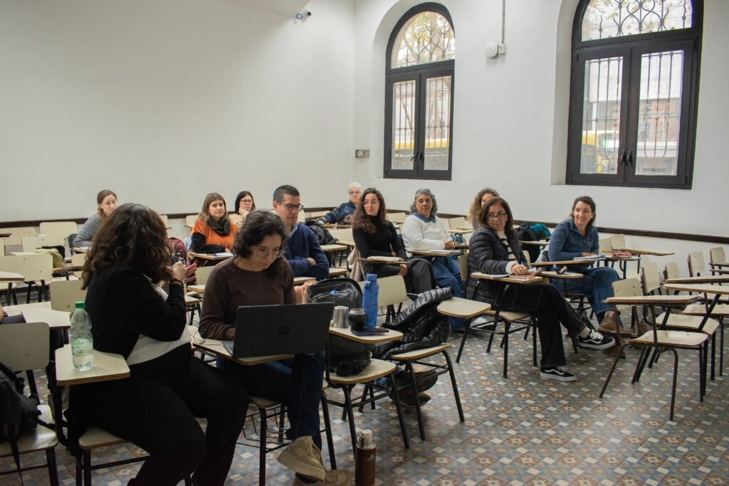 Varias personasen un salón de clase. A la izquierda, Leticia Lorier y Yanina Boria. Leticia habla, las personas presentes la miran atentamente. 